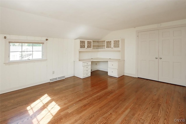 unfurnished office with dark hardwood / wood-style flooring, built in desk, and vaulted ceiling