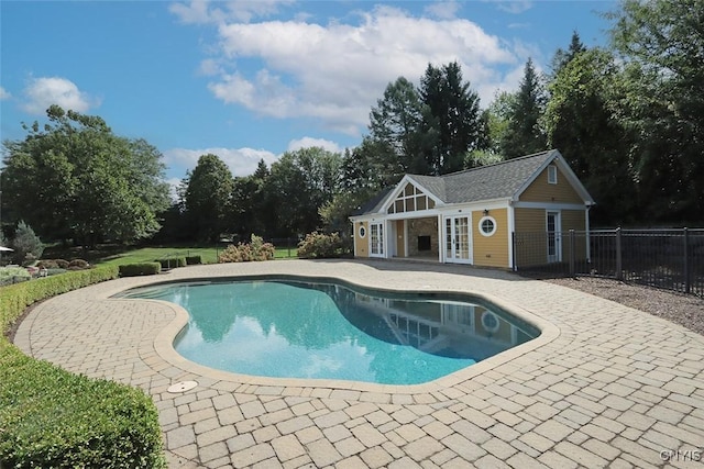 view of pool featuring an outbuilding, a patio, and french doors