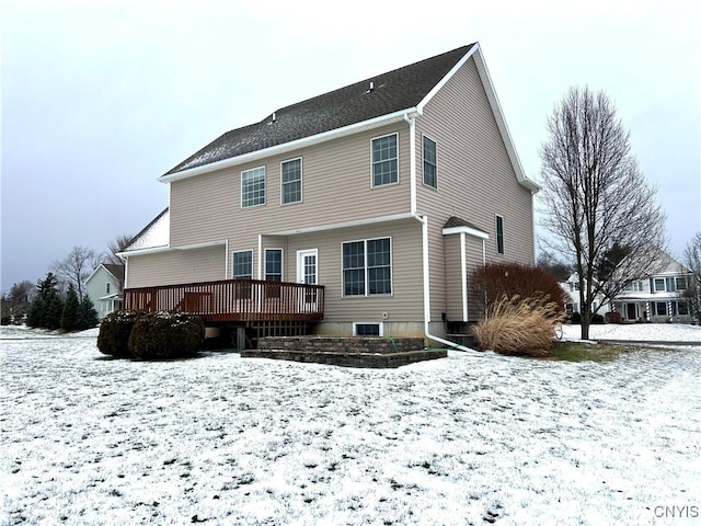 snow covered back of property with a deck