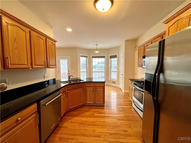 kitchen with kitchen peninsula, appliances with stainless steel finishes, light wood-type flooring, and sink