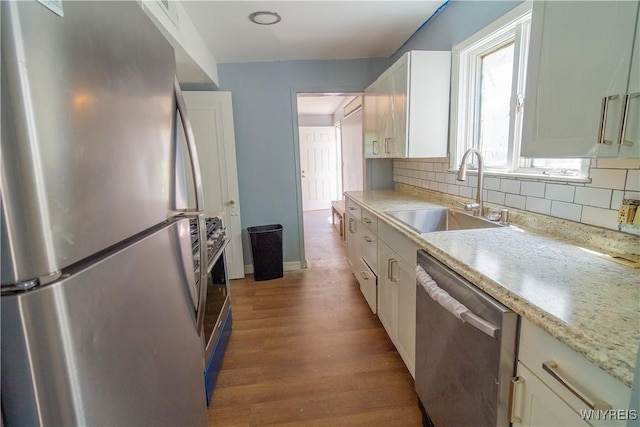 kitchen featuring white cabinets, sink, light hardwood / wood-style flooring, appliances with stainless steel finishes, and tasteful backsplash