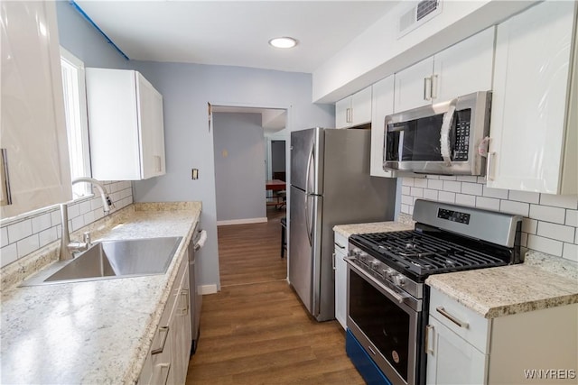 kitchen featuring white cabinetry, sink, light hardwood / wood-style floors, decorative backsplash, and appliances with stainless steel finishes