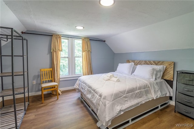 bedroom with wood-type flooring and vaulted ceiling