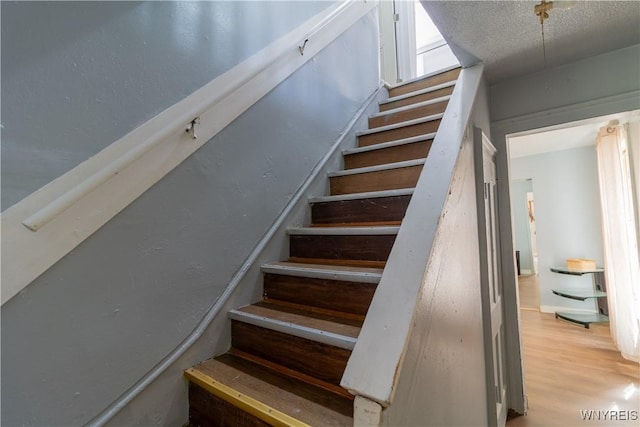 staircase featuring wood-type flooring and a textured ceiling