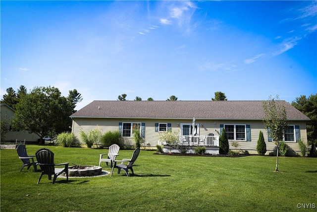 back of property featuring a fire pit, a wooden deck, and a lawn