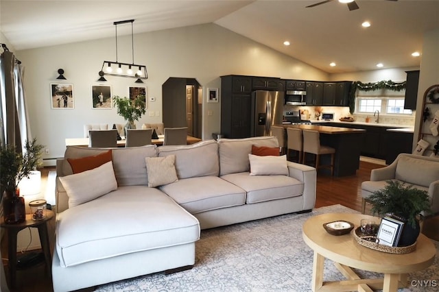 living room featuring light wood-type flooring, vaulted ceiling, ceiling fan, and sink