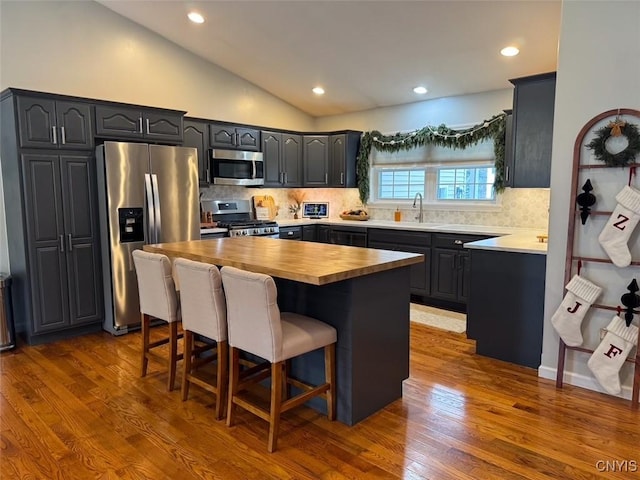 kitchen featuring a center island, a kitchen bar, butcher block countertops, dark hardwood / wood-style flooring, and stainless steel appliances