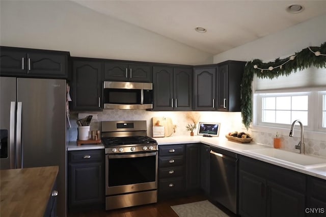 kitchen featuring backsplash, dark wood-type flooring, sink, vaulted ceiling, and appliances with stainless steel finishes