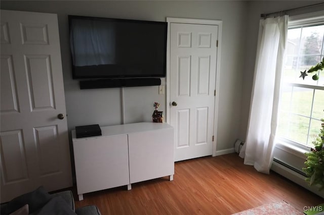 bedroom with light wood-type flooring, a baseboard radiator, and multiple windows