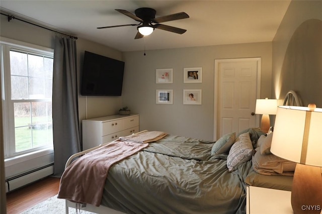 bedroom featuring ceiling fan, baseboard heating, and light hardwood / wood-style flooring