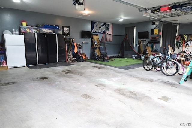 garage featuring white fridge and a garage door opener