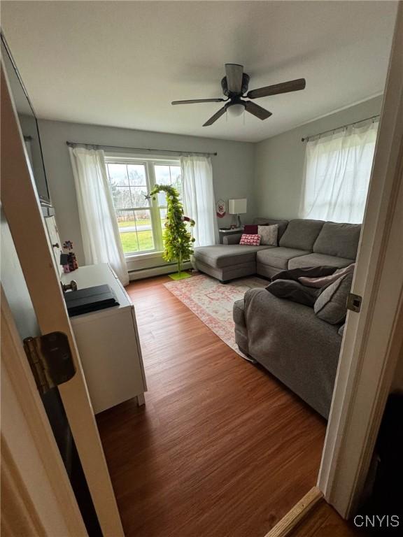 living room with ceiling fan, dark wood-type flooring, and a baseboard heating unit