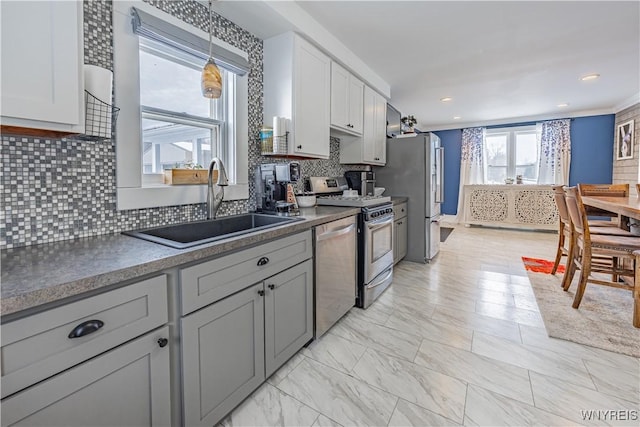 kitchen with sink, stainless steel appliances, backsplash, decorative light fixtures, and white cabinets