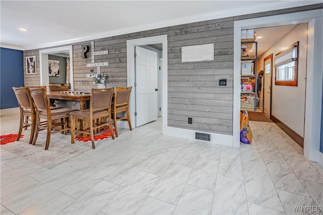 dining area featuring crown molding and wooden walls