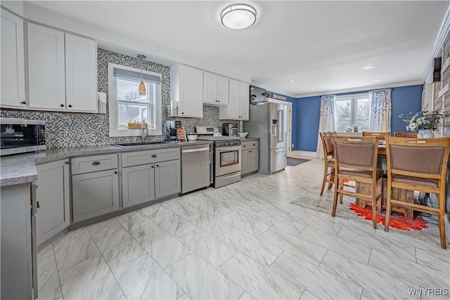 kitchen featuring decorative backsplash, sink, ornamental molding, and stainless steel appliances