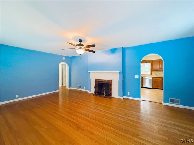 unfurnished living room featuring ceiling fan, light hardwood / wood-style flooring, and a brick fireplace