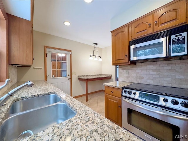 kitchen with decorative backsplash, stainless steel appliances, sink, light tile patterned floors, and hanging light fixtures