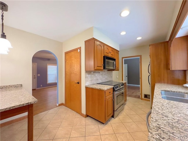 kitchen with pendant lighting, light tile patterned floors, stainless steel electric range oven, and sink