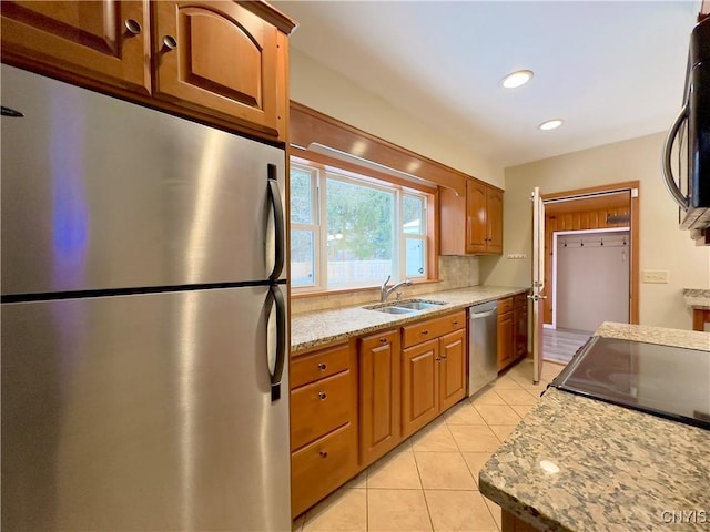 kitchen with sink, decorative backsplash, light stone countertops, light tile patterned floors, and appliances with stainless steel finishes