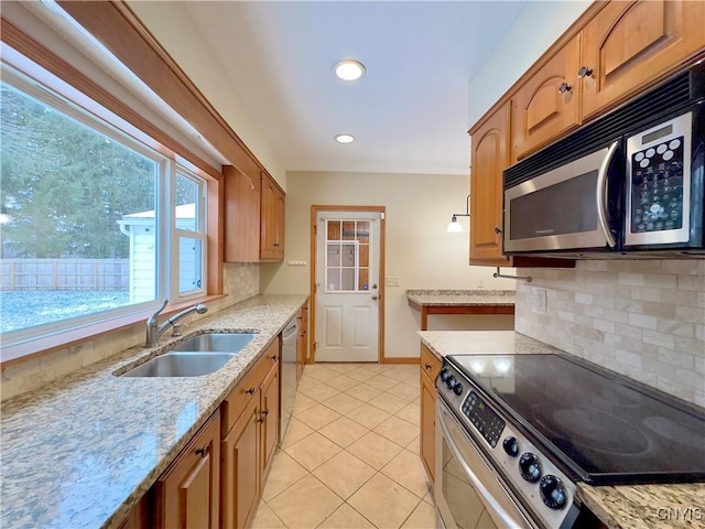 kitchen featuring sink, stainless steel appliances, tasteful backsplash, light stone counters, and light tile patterned floors