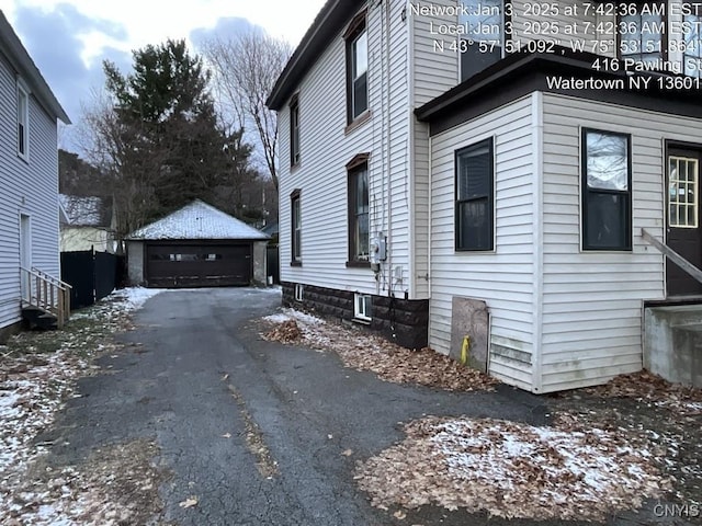 snow covered property featuring a garage and an outbuilding