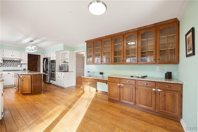 kitchen with a kitchen island, light hardwood / wood-style floors, backsplash, and appliances with stainless steel finishes