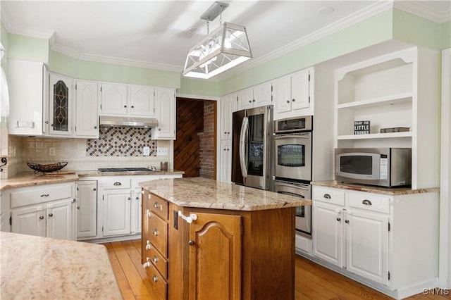 kitchen featuring white cabinets, backsplash, appliances with stainless steel finishes, a kitchen island, and ornamental molding