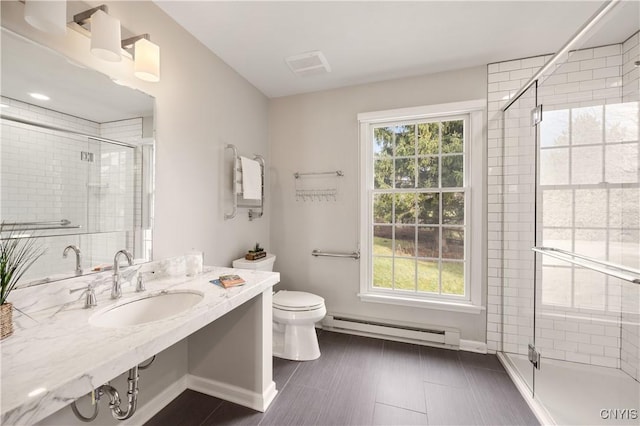 bathroom with toilet, a shower with shower door, sink, and a baseboard heating unit