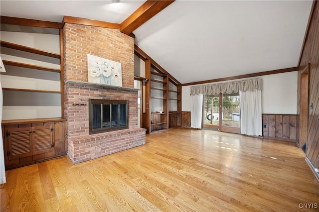 unfurnished living room featuring a brick fireplace, lofted ceiling with beams, light hardwood / wood-style flooring, and wood walls