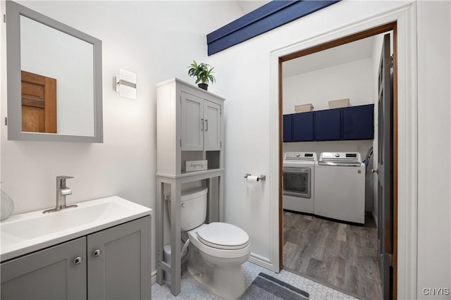 bathroom with hardwood / wood-style floors, vanity, toilet, and independent washer and dryer