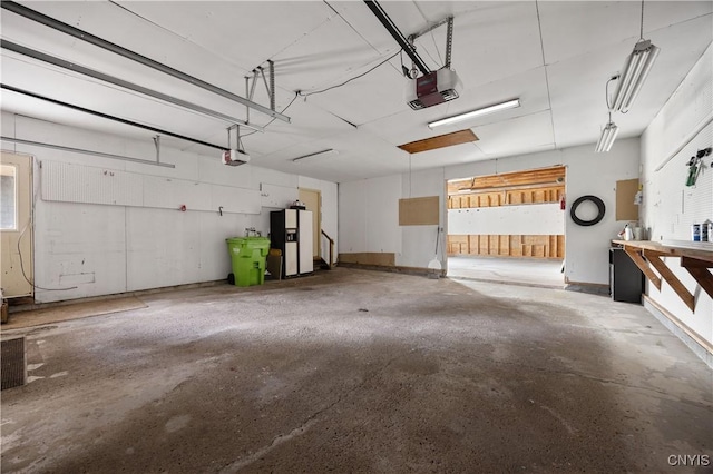 garage with a garage door opener and white refrigerator with ice dispenser