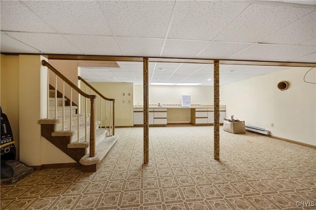 basement with a drop ceiling and a baseboard heating unit