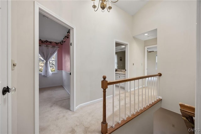 corridor with light carpet and a chandelier