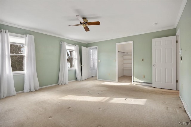 unfurnished bedroom featuring crown molding, ceiling fan, a spacious closet, light colored carpet, and a closet