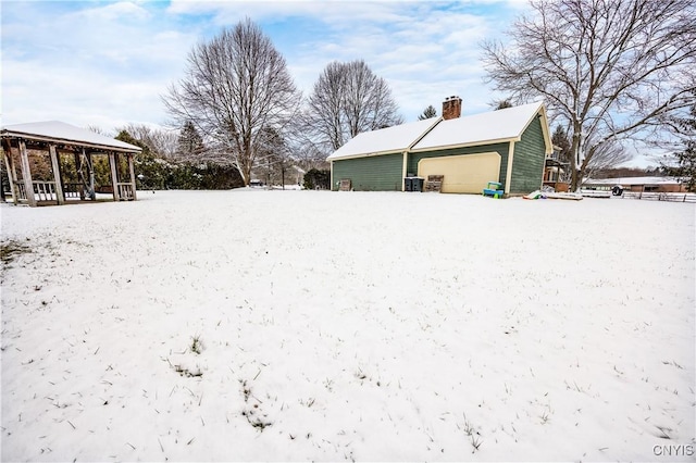 yard layered in snow featuring an outbuilding and a garage