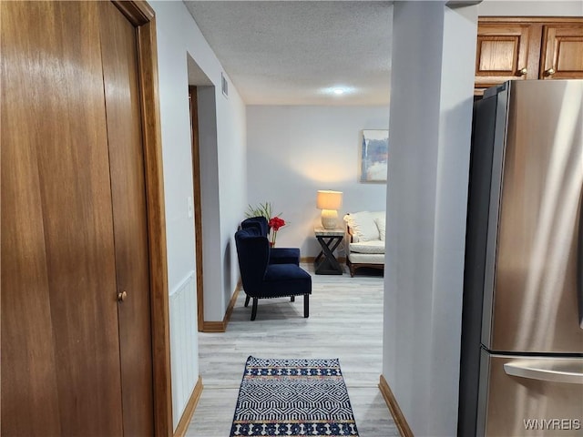 hallway featuring light hardwood / wood-style flooring and a textured ceiling