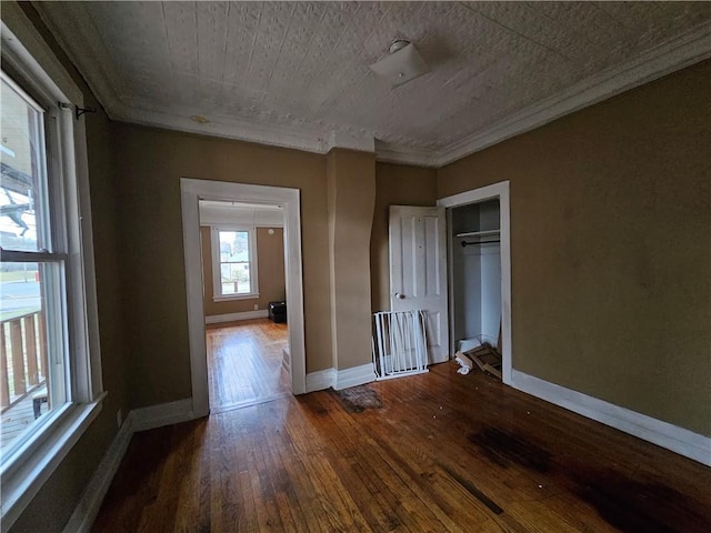 unfurnished bedroom featuring ornamental molding, dark wood-type flooring, and a closet