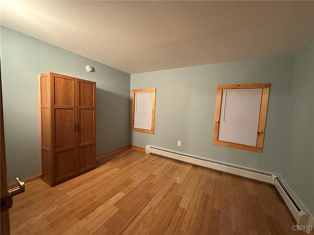 unfurnished bedroom with light wood-type flooring and baseboard heating