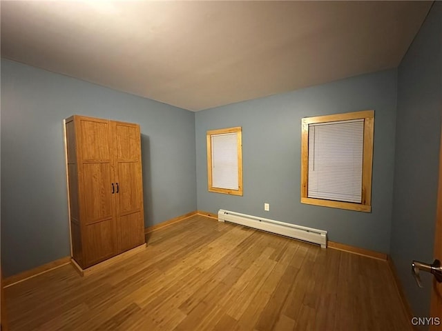 unfurnished bedroom with a baseboard radiator and hardwood / wood-style flooring