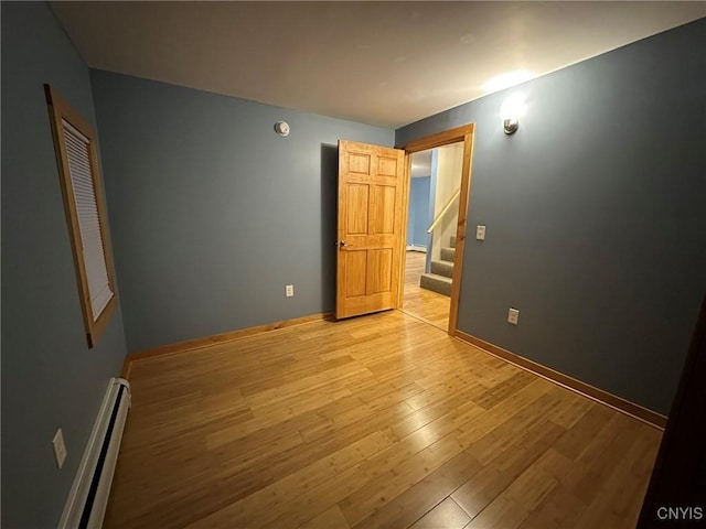 unfurnished bedroom with light wood-type flooring and a baseboard radiator