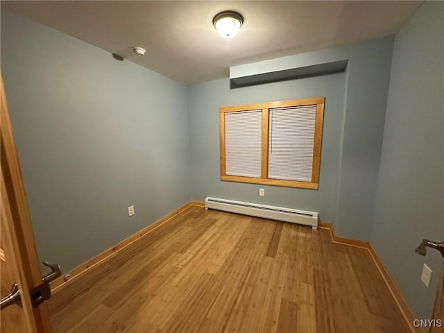 spare room featuring baseboard heating and light wood-type flooring