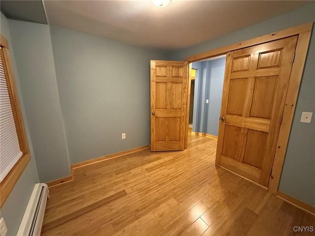 unfurnished bedroom with a baseboard radiator and light hardwood / wood-style floors