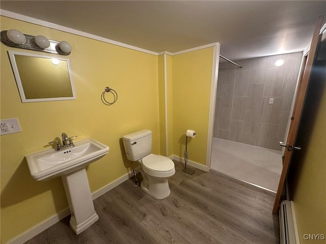 bathroom with hardwood / wood-style floors, toilet, a baseboard radiator, and tiled shower