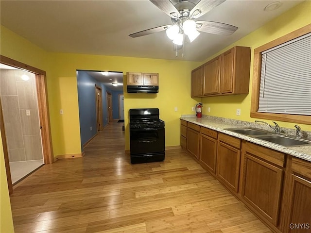 kitchen with gas stove, light hardwood / wood-style flooring, ceiling fan, and sink