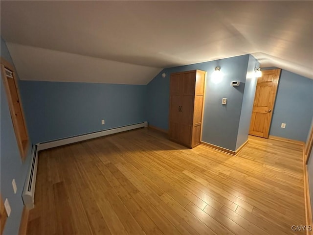 additional living space with light hardwood / wood-style flooring, a baseboard radiator, and vaulted ceiling