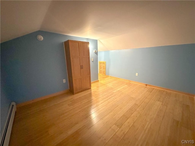 bonus room with baseboard heating, light hardwood / wood-style floors, and lofted ceiling