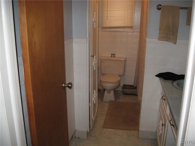 bathroom with toilet, vanity, tile walls, and tile patterned floors