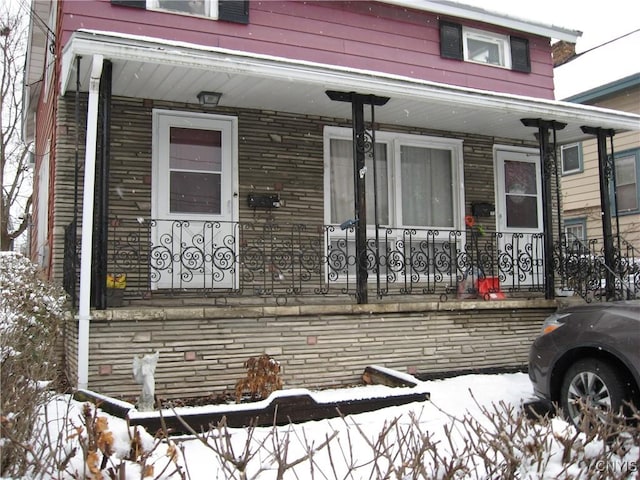 snow covered property entrance featuring covered porch