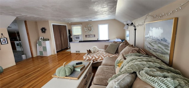 living room featuring lofted ceiling, visible vents, and wood finished floors