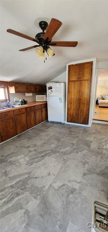 kitchen featuring vaulted ceiling, white appliances, and brown cabinetry